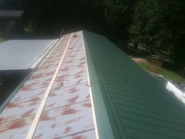 Old rusted panels beside newly installed green metal roofing — Wind Damage Roof Repair by Roofing Brothers in Maquon