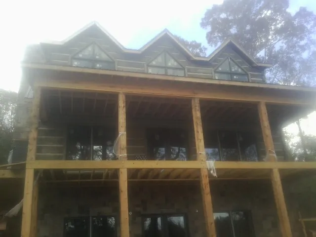 Dormers and porch framing on a large log home under construction — Roof Coating work by our crew in Maquon
