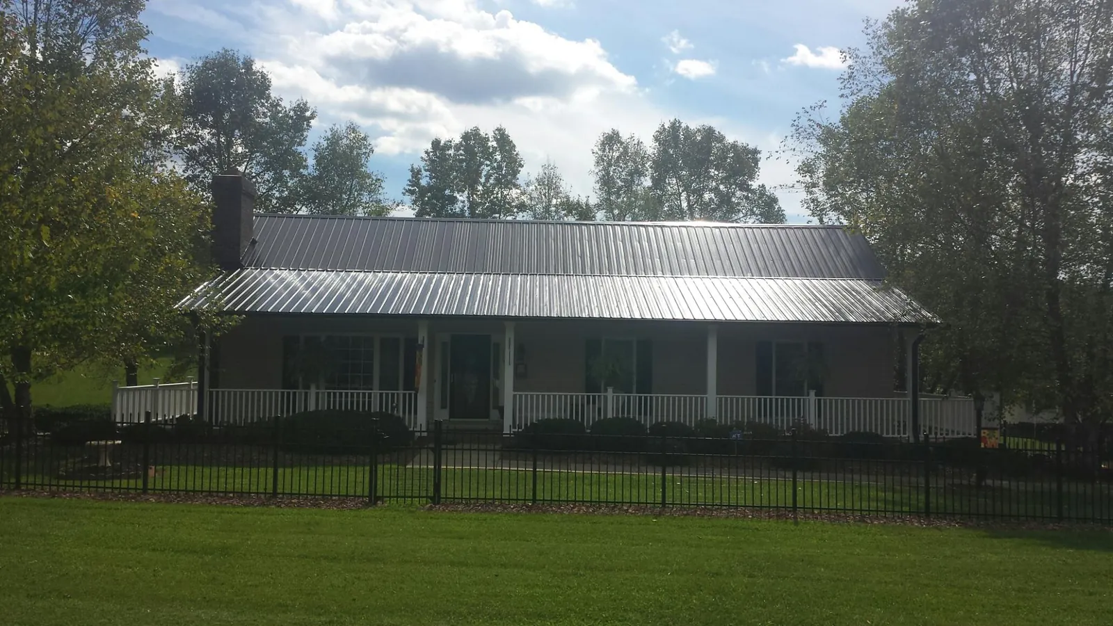 Gray metal roof on a brick ranch with a full width front porch — Gutter Guard Installation work by our crew in Maquon