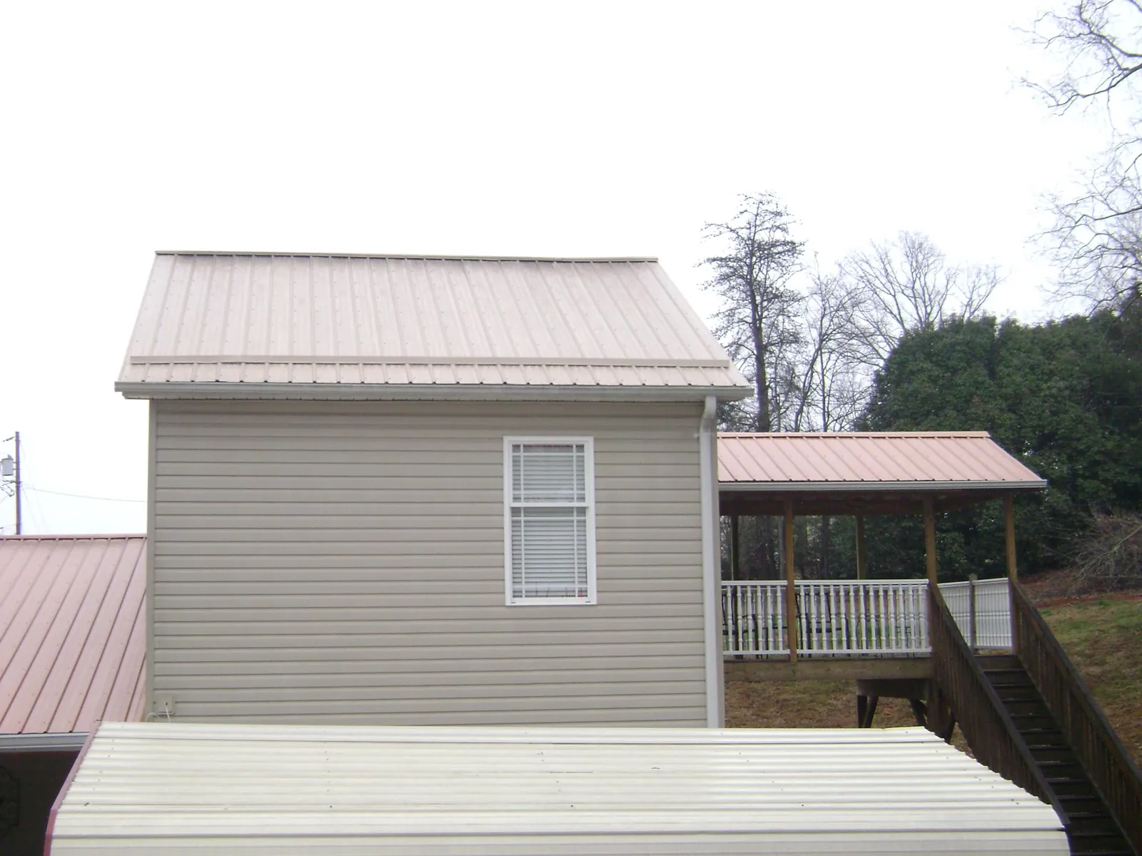 Tan metal roofs on a two story addition and attached porch, from a Roof Replacement job in Maquon
