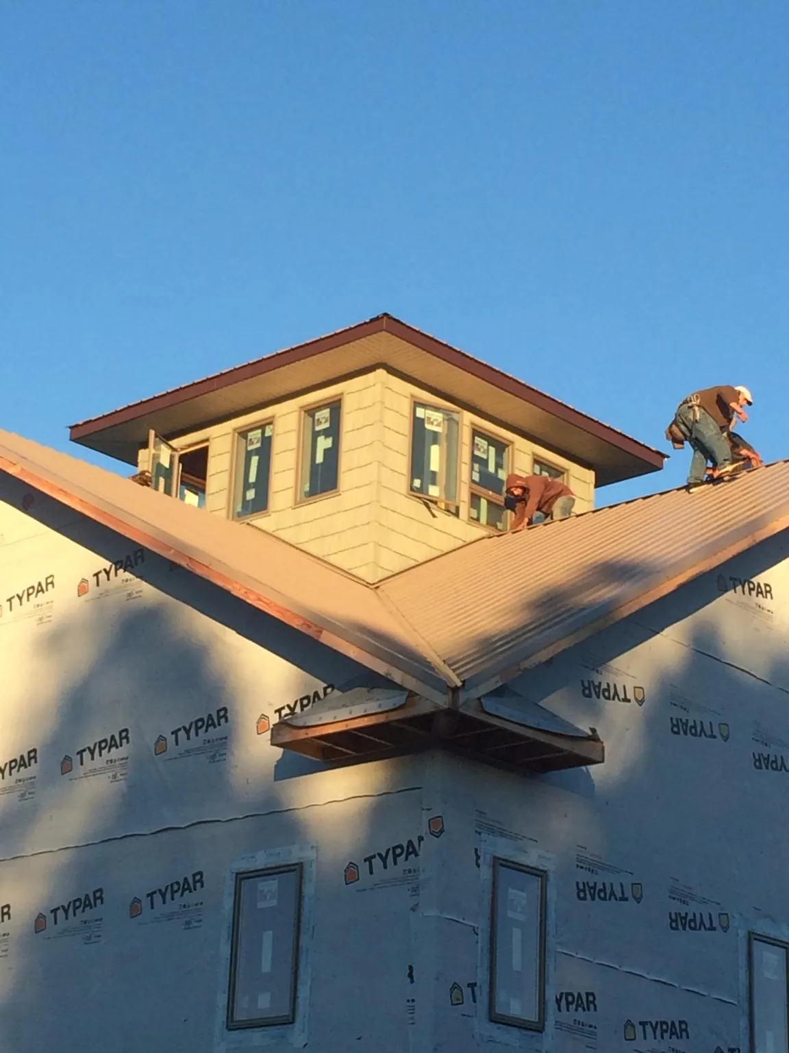 Roofers working around a rooftop cupola on a new metal roof at sunset — Roof Waterproofing in Maquon by Roofing Brothers